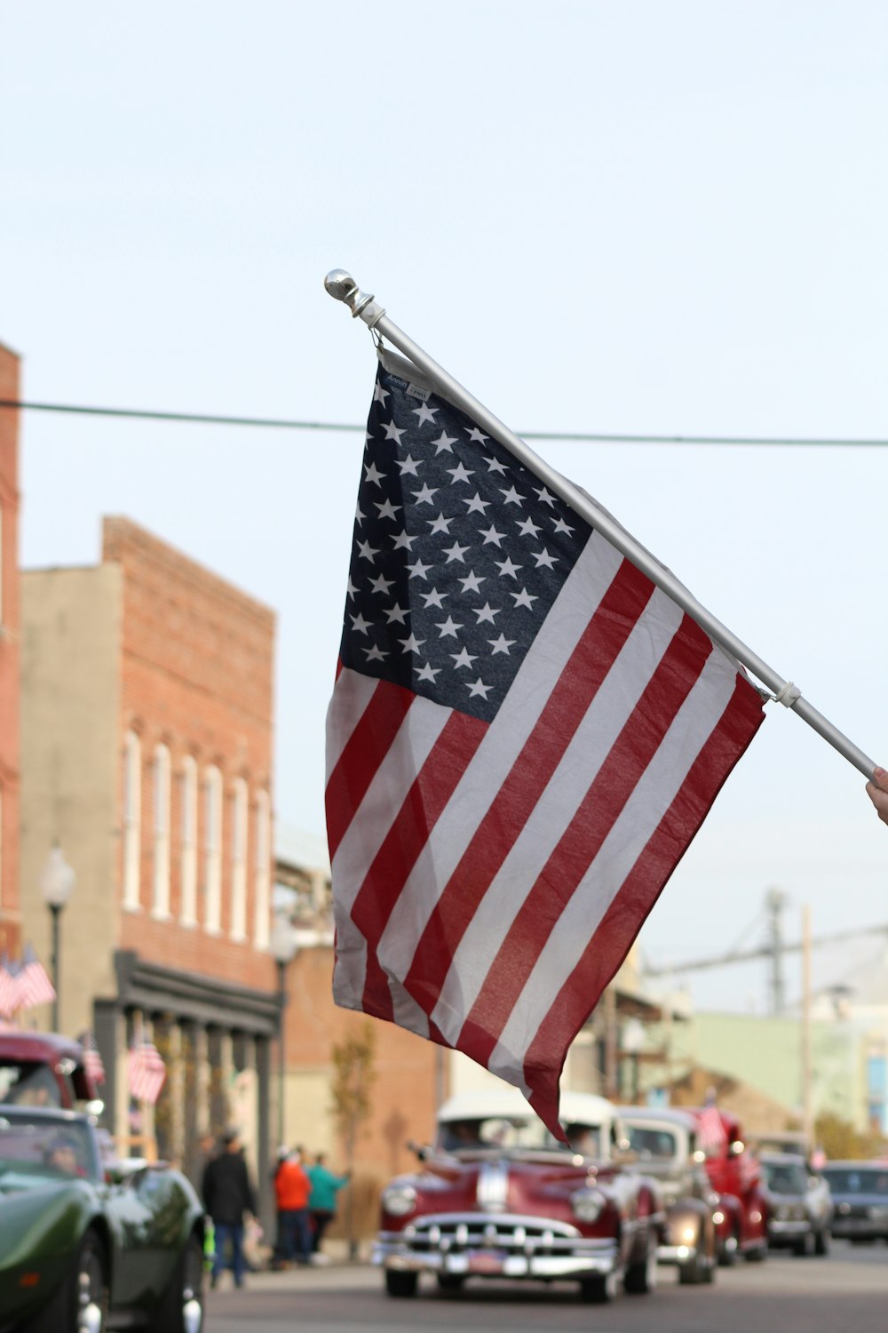 The American Flag flows at the annual Veterans Day Parade in Owensboro, Kentucky, as the Antique Car Club drives by.